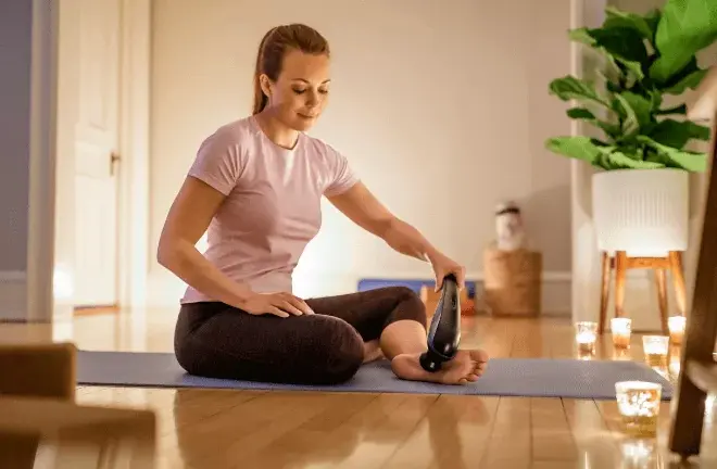 Woman on yoga mat using Wahl deep tissue massager.
